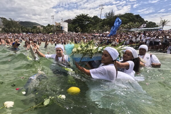 Devotees wade through Arpoador Beach carrying a boat filled with offerings during an annual celebration honoring Yemanja, the African goddess of the sea, in Rio de Janeiro, Sunday, Feb. 2, 2025. (AP Photo/Bruna Prado)