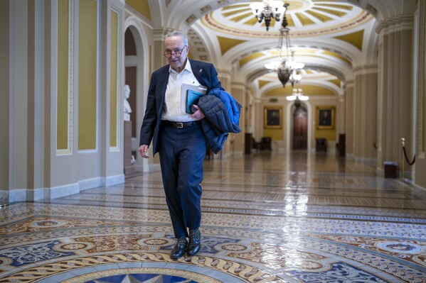 Senate Majority Leader Chuck Schumer, D-N.Y., arrives as the Senate prepares to take a procedural vote on an emergency spending package that would provide military aid to Ukraine and Israel, replenish U.S. weapons systems and provide food, water and other humanitarian aid to civilians in Gaza, at the Capitol in Washington, Sunday, Feb. 11, 2024. (AP Photo/J. Scott Applewhite)