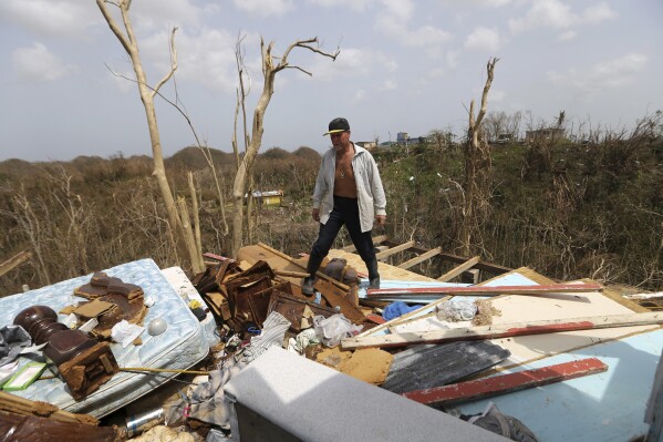 FILE - Jose Trinidad walks on what's left of his home in Montebello, Puerto Rico, in the aftermath of Hurricane Maria, Sept. 26, 2017. With warmer oceans serving as fuel, Atlantic hurricanes are now more than twice as likely as before to rapidly intensify from wimpy minor hurricanes to powerful and catastrophic, a study said Thursday, Oct. 19, 2023. (AP Photo/Gerald Herbert, File)