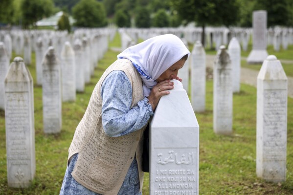 Sefika Mustafic kisses the grave of her son, victim of the Srebrenica genocide, at the Memorial Center in Potocari, Bosnia, Wednesday, May 22, 2024. On May 23, the United Nations General Assembly will be voting on a draft resolution declaring July 11 the International Day of Reflection and Commemoration of the 1995 genocide in Srebrenica. (AP Photo/Armin Durgut)