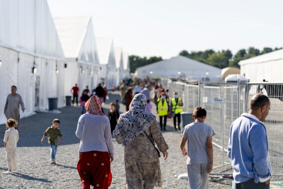 FILE - Afghan refugees walk through an Afghan refugee camp at Joint Base McGuire Dix Lakehurst, N.J., on Sept. 27, 2021. More than 840,000 Afghans who applied for a resettlement program aimed at people who helped the U.S. war effort in Afghanistan are still there waiting, according to a report that lays out the challenges with a program intended to help America's allies in the two-decade long conflict. (AP Photo/Andrew Harnik, File)