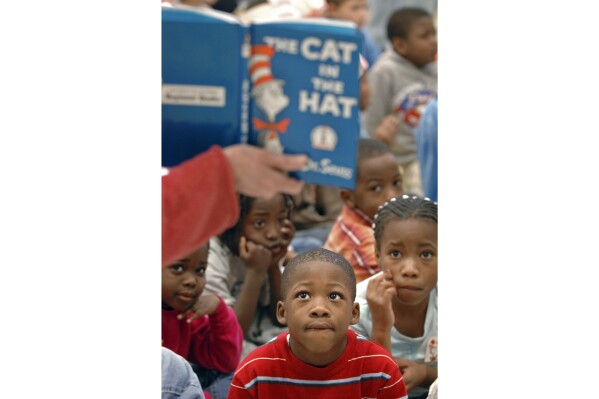 FILE - First graders listen as "The Cat in the Hat" is read to them at Chapman Elementary School in Spartanburg, S.C., March 2, 2007, in honor of Dr. Seuss' birthday. Dr. Seuss Enterprises is celebrating the iconic children's author's 120th birthday with a free giveaway of “The Cat in the Hat” to U.S. residents who have a baby born this March 2, 2024. (Tim Kimzey/Spartanburg Herald-Journal via AP, File)