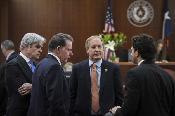 FILE - Texas Attorney General Ken Paxton, second from right, talks with his defense attorneys Philip Hilder, from left, Dan Cogdell, and Anthony Osso, Jr., after Paxton appeared in the 185th District Court for a hearing in his securities fraud case, Friday, Feb. 16, 2024, at the Harris County criminal courthouse in Houston. Paxton was expected back in court Tuesday, March 26, 2024, and closer than ever before to standing trial on felony securities fraud charges that have shadowed the Republican for nearly a decade. (Jon Shapley/Houston Chronicle via AP, File)