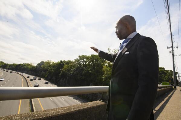 Tennessee State Rep. Harold Love, Jr. gestures toward an area he is supporting to expand a bridge and make a cap over I-40, Monday, July, 19, 2021, on the north side of Nashville, Tenn. Love Jr.'s father, a Nashville city councilman, was forced to sell his family home nearby, to make way for the highway, but put up a fight in the 1960s against the rerouting of Interstate 40 because he believed it would stifle and isolate Nashville's Black community. (AP Photo/John Amis)