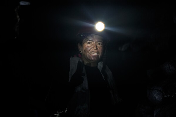 Emerald miner Janeth Paez, 45, stands inside the tunnel of an informal mine near the town of Coscuez, Colombia, Wednesday, Feb. 28, 2024. Deep inside mountain tunnels where the heat is so intense it causes headaches, women with power tools are chipping away at boulders in search of the green gems. (AP Photo/Fernando Vergara)