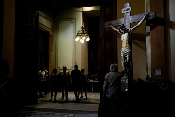 FILE - A man touches a statue depicting a crucified Jesus Christ, at the Metropolitan Cathedral in Buenos Aires, Argentina, March 6, 2023. A 2019 national poll on religious beliefs in Argentina displayed the lack of fervor for Pope Francis when only 27% described the pope as a global leader who denounces injustices. Some 40% said they are indifferent to the pontiff and 27% said he is too involved in politics, according to the poll by the publicly funded CONICET institute. (AP Photo/Natacha Pisarenko, File)