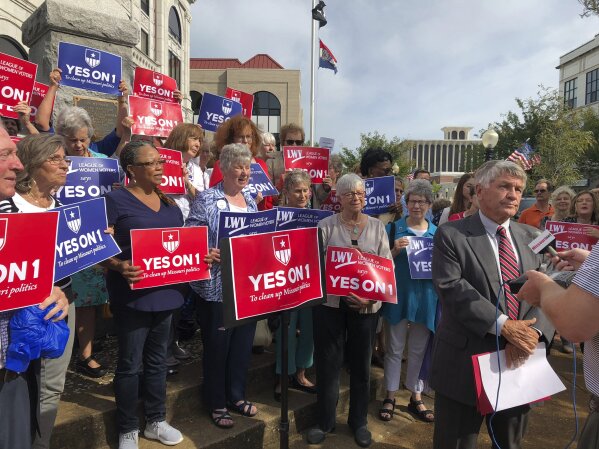 FILE - In this Aug. 31, 2018 file photo, supporters of Missouri's redistricting ballot measure hold signs behind former state Sen. Bob Johnson as he serves as their spokesman during a press conference outside the Cole County Courthouse in Jefferson City, Mo .Two years after Missouri voters enacted a first-of-its-kind initiative intended to create “partisan fairness” in voting districts, they have changed their minds. (AP Photo/David A. Lieb, File)