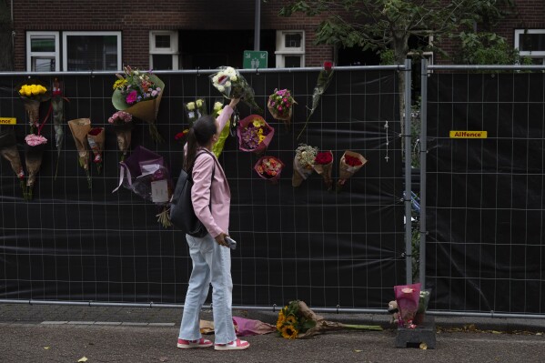 A woman put flowers at the scene of a shooting in Rotterdam, Netherlands, Friday, Sept. 29, 2023. Police in the Netherlands said a lone gunman wearing a bulletproof vest opened fire in an apartment and a hospital in the Dutch port city of Rotterdam, Thursday, Sept. 28, 2023, killing three people, including a 14-year-old girl. (AP Photo/Peter Dejong)