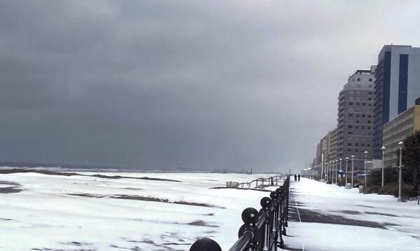 Snow covers the Virginia Beach oceanfront, Saturday, Jan. 22, 2022 in Virginia Beach, Va.  A layer of ice and a blanket of snow has covered coastal areas stretching from South Carolina to Virginia. The winter weather system that entered the region on Friday brought colder temperatures and precipitation not often seen in the region. (Stacy Parker/The Virginian-Pilot via AP)