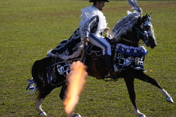 Un caballero cristiano dispara un arma durante una recreación de una batalla en las Cavalhadas, o Fiesta del Espíritu Santo, en Pirenópolis, estado de Goiás, Brasil, el lunes 9 de junio de 2025. (Foto AP/Eraldo Peres)