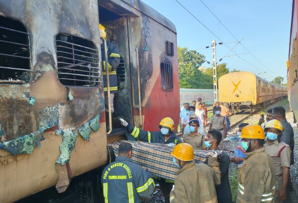 Firefighters hold a stretcher to carry bodies from a train coach where fire erupted in Madurai, in the southern Indian state of Tamil Nadu, Satursday, Aug. 26, 2023. A gas cylinder smuggled in by some passengers caused the fire killing nine people, according to a statement by the Southern Railway. (AP Photo)