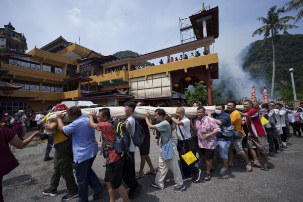 Devotees carries a giant canvas of sacred "Thangka" to display under the sun during Wesak day celebration in Ipoh, Malaysia, Wednesday, May 22, 2024. (AP Photo/Vincent Thian)