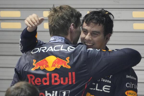 Red Bull driver Sergio Perez, right, of Mexico is congratulated by teammate Max Verstappen of the Netherlands after winning the Singapore Formula One Grand Prix, at the Marina Bay City Circuit in Singapore, Sunday, Oct.2, 2022. (AP Photo/Vincent Thian )
