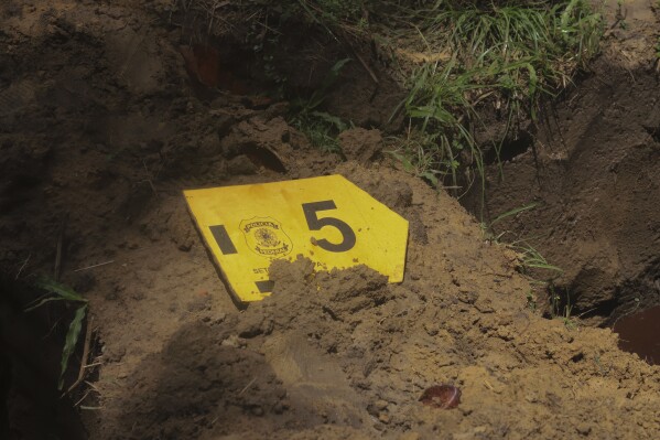 A label with the number 5 to mark one of nine unidentified migrants, sits on a freshly dug grave during a burial service, at Sao Jorge cemetery, in Belem, Para state, Brazil, Thursday, April 25, 2024. The bodies of nine migrants found on an African boat off the northern coast of Brazil's Amazon region were buried Thursday with a solemn ceremony in a cemetery. (AP Photo/Paulo Santos)