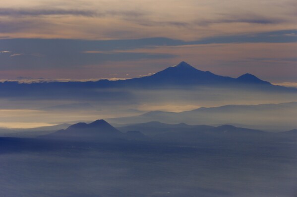 FILE - Mexico's highest peak and the third highest in North America, Pico de Orizaba, or Citlaltepetl mountain, rises above the morning mist as seen from a Mexican Navy aircraft on a volcano monitoring mission in Mexico, July 23, 2013. On Feb. 21, 2024, authorities said two people died and another remains missing on Pico de Orizaba, the highest mountain in the country. (AP Photo/Dario Lopez-Mills, File)
