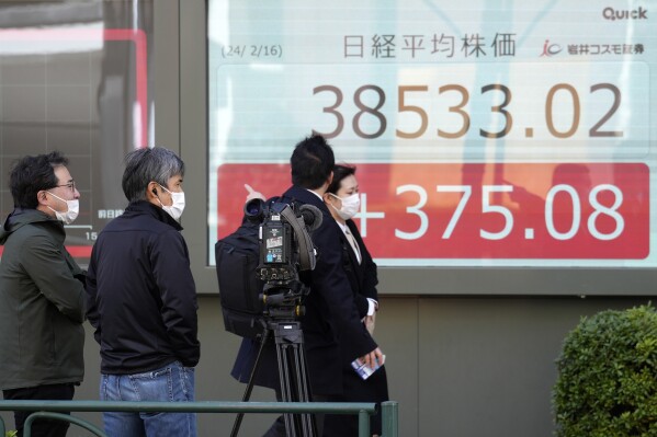 TV crew members film an electronic stock board showing Japan's Nikkei 225 index at a securities firm as people pass by Friday, Feb. 16, 2024, in Tokyo. Shares advanced in Asia on Friday, with Tokyo's benchmark Nikkei 225 index trading near a record high, 34 years after it peaked and then plunged with the collapse of Japan's financial bubble. (APPhoto/Eugene Hoshiko)