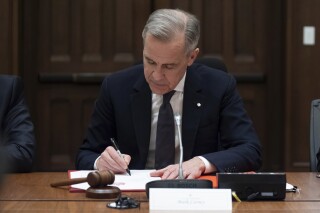 Prime Minister Mark Carney signs a document during cabinet meeting on Parliament Hill, Friday, March 14, 2025 in Ottawa. (Adrian Wyld/The Canadian Press via AP)