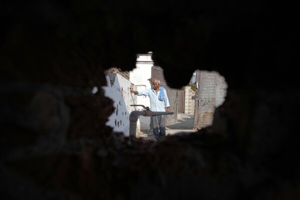A villager shows the wall of his house riddled with shrapnels from Pakistani artillery shelling at RS Pura, along the International Border, India, Monday, May 12, 2025. (AP Photo/Channi Anand)