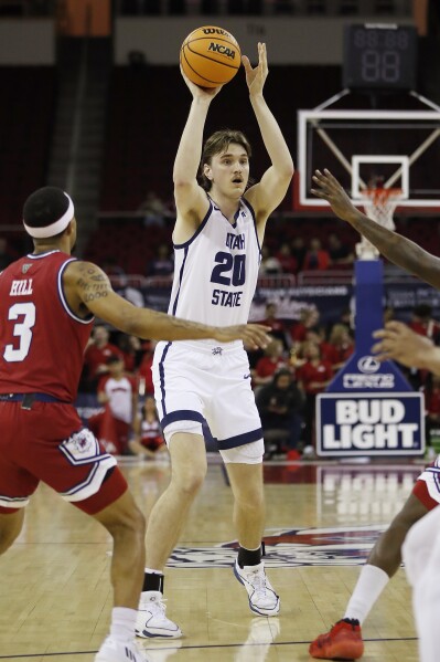 Isaac Johnson, de Utah State, pasa contra Isaiah Hill, de Fresno State, durante la primera mitad de un partido de baloncesto universitario de la NCAA en Fresno, California, el martes 27 de febrero de 2024. (Foto AP/Gary Kazanjian)