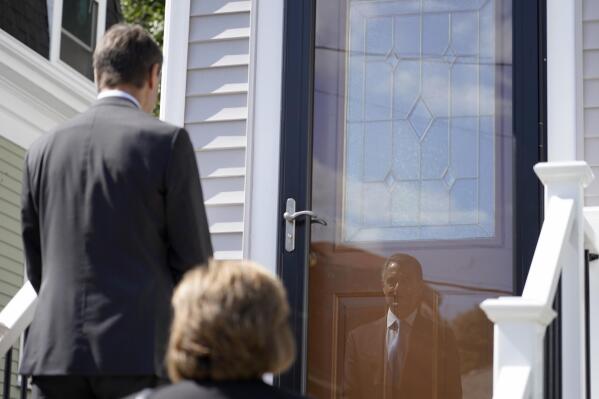 Dan Sideris is reflected in a front storm door as he and his wife, Carrie Sideris, of Newton, Mass., return to door-to-door visits as Jehovah's Witnesses, Thursday, Sept. 1, 2022, in Boston. After more than two and a half years on hiatus due to the coronavirus pandemic, members are reviving a religious practice that the faith considers crucial and cherished. (AP Photo/Mary Schwalm)