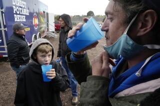 Connor Sonnenberg, foreground left, and Billy Kinn, foreground right, drink wastewater that was sterilized at the PureWater Colorado Mobile Demonstration using a method that involves carbon-based purification, Thursday, Oct. 14, 2021, in Colorado Springs, Colo. Across the U.S., cities are increasingly embracing the idea of sterilizing wastewater from toilets, sinks and factories, and piping it back into homes and businesses for drinking. (AP Photo/Brittany Peterson)