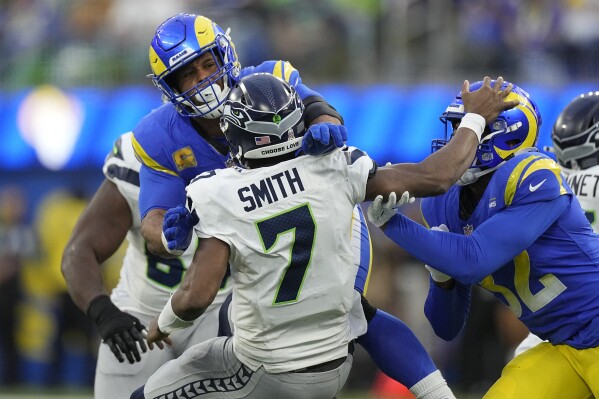 Seattle Seahawks quarterback Geno Smith (7) is injured while being tackled by Los Angeles Rams defensive tackle Aaron Donald, left, and linebacker Ochaun Mathis, right, during the second half of an NFL football game Sunday, Nov. 19, 2023, in Inglewood, Calif. (AP Photo/Mark J. Terrill)