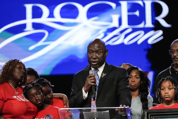 Trial lawyer Benjamin Crump speaks as the family of slain airman Roger Fortson look on during a news conference describing details of the airman's death, Thursday, May 16, 2024, in Stonecrest, Ga. (AP Photo/Mike Stewart)