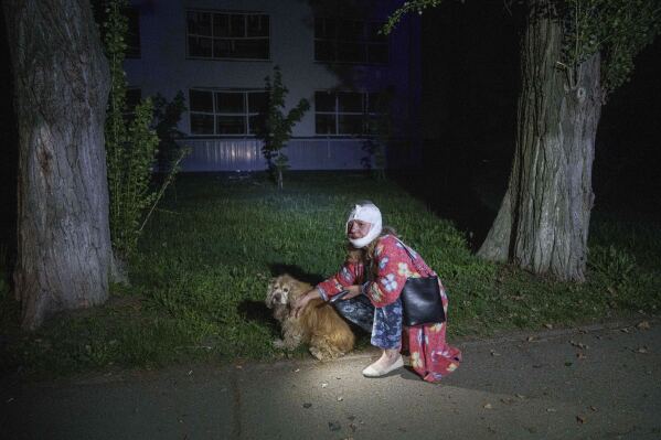 An injured woman sits with her dog near a house destroyed by a Russian airstrike in a residential neighborhood in Kyiv, Ukraine, on Thursday, April 24, 2025. (AP Photo/Evgeniy Maloletka)