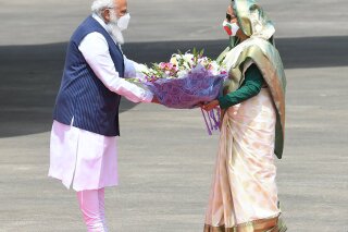 In this photo provided by Prime Minister of India Narendra Modi's twitter handle, Indian Prime Minister Narendra Modi receives a bouquet of flowers from Bangladesh's Prime Minister Sheikh Hasina in Dhaka, Bangladesh, Friday, March 26, 2021. Modi arrived in Bangladesh’s capital on Friday to join celebrations marking 50 years of the country's independence, but his trip was not welcomed by all. The two-day visit, his first foreign trip since the coronavirus pandemic began last year, will also include joining commemorations for 100 years since the birth of independence leader Sheikh Mujibur Rahman, the father of current Prime Minister Sheikh Hasina. (Prime Minister of India Narendra Modi's twitter handle via AP Photo)