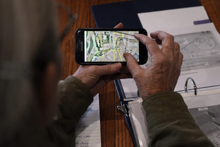 Gayna Salinas shows a map on her phone of land owned by Anson Resources, who plans to extract lithium, Thursday, Jan. 25, 2024, in Green River, Utah. (AP Photo/Brittany Peterson)