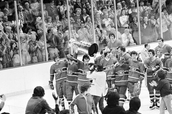 FILE - Montreal Canadiens' captain Serge Savard raises the Stanley Cup over his head as the Canadiens begin to march around the Boston Garden after winning the final game of the Stanley Cup series Saturday night, May 16, 1977 in Boston, Mass. The Canadiens won the game in sudden death overtime 2-1, to win the series in a four-game sweep. With the Boston Bruins now chasing the points and wins marks, members of the record-setting Canadiens, Red Wings and Lightning understand what it's like to be this dominant all season.(AP Photo/File)