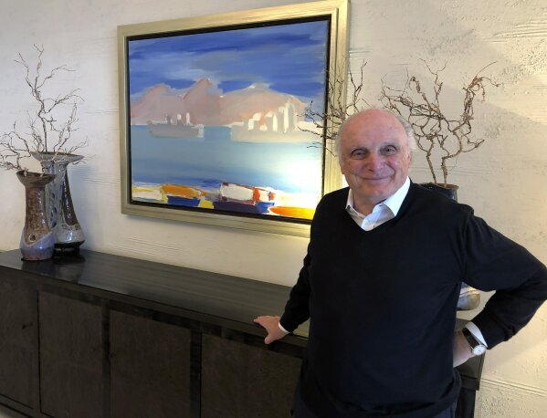 In this photo taken on Monday, March 2, 2020, billionaire art dealer David Nahmad poses in front of a seascape by artist Nicolas de Stael in Nahmad's home in Monaco. Nahmad has spent decades accumulating what he believes is now the world's largest private collection of works by Pablo Picasso, but he is about to part with one of them. A still life that Picasso painted in 1921 is being raffled off for charity in Paris this month with tickets at 100 euros each. (AP Photo/John Leicester)