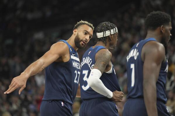 Minnesota Timberwolves center Rudy Gobert (27), left, speaks with forward Jaden McDaniels (3), middle, during the first half of an NBA basketball game against the Milwaukee Bucks, Friday, Nov. 4, 2022, in Minneapolis. (AP Photo/Abbie Parr)