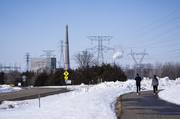 FILE - People walk on a trail at the Montissippi County Park near the Xcel Energy Monticello Generating Plant, a nuclear power plant, in Monticello, Minn., March 24, 2023. Xcel Energy, the energy company responsible for leaking radioactive material from its nuclear plant in Monticello, in recent months has announced that it will build an underground metal barrier to keep affected groundwater away from the nearby Mississippi River. Xcel Energy said construction will last several weeks and should begin between Friday, Aug. 18, and Monday, Aug. 21, according to a statement posted on the city of Monticello's website Thursday, Aug. 17. (Renee Jones Schneider/Star Tribune via AP, File)