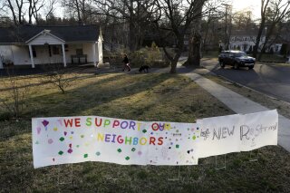 A sign showing support for residents is displayed on a lawn in New Rochelle, N.Y., Wednesday, March 11, 2020. State officials are shuttering several schools and houses of worship for two weeks in the New York City suburb and sending in the National Guard to help with what appears to be the nation's biggest cluster of coronavirus cases, Gov. Andrew Cuomo said Tuesday. (AP Photo/Seth Wenig)
