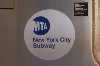 FILE - The MTA logo is seen on the side of a New York City subway car, April 23, 2020, in the Queens borough of New York. Police in New York City are searching for a man who slashed Alton Scott, a subway conductor, in the neck on Thursday, Feb. 29, 2024. Scott was slashed in the neck as he put his head out a window to make sure the track was clear, the union representing transit workers said. (AP Photo/Mark Lennihan, File)