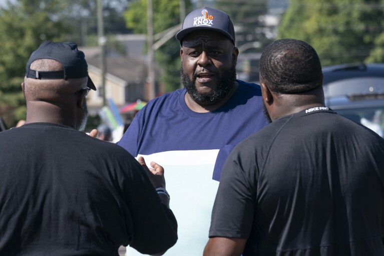 Kodi Mills, center, of Turn Up Knox talks with people enjoying the Lonsdale Neighborhood Homecoming celebration Saturday, Aug. 5, 2023 in Knoxville, Tenn. (AP Photo/George Walker IV)