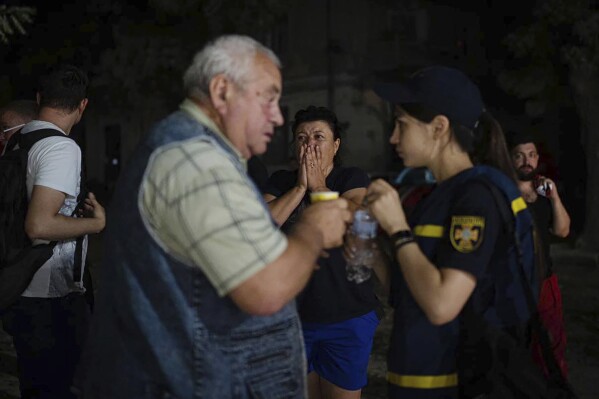 In this image provided by the Ukrainian Emergency Service, people react after a Russian attack at a residential area in Odesa, Ukraine, Thursday, July 20, 2023. (Pavlo Petrov/Ukrainian Emergency Service via AP)