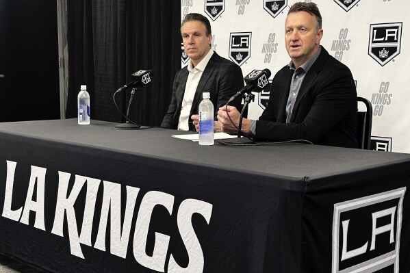 Los Angeles Kings head coach Jim Hiller, left, and general manager Rob Blake speak to reporters at the NHL hockey club's training complex in El Segundo, Calif., Thursday, May 23, 2024. Hiller has been named the Kings' permanent head coach after guiding them to a first-round playoff exit as the interim head coach this season. (AP Photo/Greg Beacham)