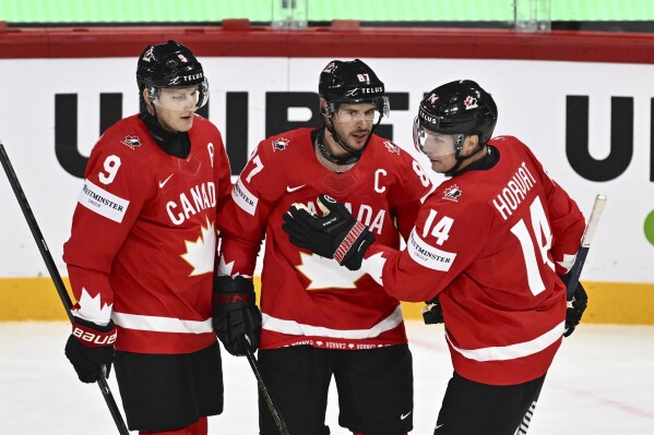 Canada's Sidney Crosby, center, celebrates after scoring with teammates Nate MacKinnon, left, and Bo Horvat during the IIHF Ice Hockey World Championship group A match between Canada and France at Avicii Arena in Stockholm, Sweden, Tuesday, May 13, 2025. (Anders Wiklund/TT via AP)