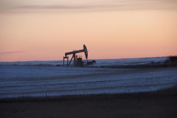 FILE -In this Feb. 25, 2015 photo, a pump jack for pulling oil from the ground is seen near New Town, N.D. The Biden administration has reached a legal settlement requiring officials to re-examine potential climate damages from oil and gas leases in Montana and North Dakota that were put up for sale under the Trump administration. The settlement involves public lands totaling 91 square miles. It was detailed in documents filed Tuesday, Sept. 6, 2022 in U.S. District Court in Montana. (AP Photo/Matthew Br, File)