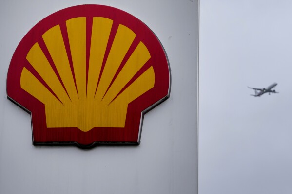 FILE - An aircraft passes a sign at a shell petrol station in London, Thursday, Feb. 2, 2023. Shell has reported that it earned nearly $5.1 billion in the second quarter. London-based oil giant Shell saw profits tumble by nearly a third in 2023 as a result of lower oil and natural gas prices, which had surged the year before in the wake of Russia's invasion of Ukraine. (AP Photo/Kirsty Wigglesworth, File)