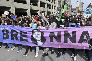 FILE - In this March 13, 2021 file photo, Tamika Palmer, center, the mother of Breonna Taylor, leads a march through the streets of downtown Louisville on the one year anniversary of her death in Louisville, Ky. The Justice Department said Tuesday, Sept. 14, it is curtailing federal agents’ use of so-called “no-knock” warrants — which allow law enforcement agents to enter a home without announcing their presence — and would also prohibit its agents from using chokeholds in most circumstances. The updated policy follows the March 2020 death of Breonna Taylor, who was shot and killed by police in her home during a no-knock warrant and whose death led to months of mass protests over racial injustice in policing and the treatment of Black people in the United States. (AP Photo/Timothy D. Easley, File)