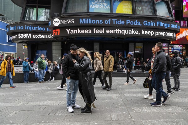 People walk around Times Square as news tickers display news about the earthquake on Friday April 5, 2024 in New York. An earthquake centered between New York and Philadelphia shook skyscrapers and suburbs across the northeastern U.S. for several seconds Friday morning, causing no major damage but startling millions of people in an area unaccustomed to such tremors. (AP Photo/Brittainy Newman)