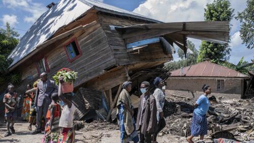 People walk next to a house destroyed by the floods in the village of Nyamukubi, South Kivu province, in Congo, Saturday, May 6, 2023. The death toll from flash floods and landslides in eastern Congo has risen according to the governor and authorities in the country's South Kivu province. (AP Photo/Moses Sawasawa)