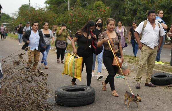 Commuters walk into the city due to the roads blocked by demonstrators in protest against the imprisonment of the opposition leader and governor of Santa Cruz Luis Fernando Camacho, on the outskirts of Santa Cruz, Bolivia, Tuesday, Jan. 3, 2023. Prosecutors in Bolivia on Dec. 29, 2022, called for Camacho to be remanded in custody for six months in prison while he faces terrorism charges. (AP Photo/Juan Karita)