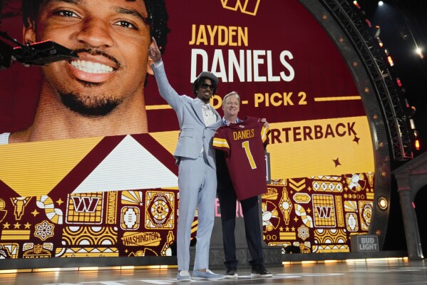 LSU quarterback Jayden Daniels celebrates beside NFL Commissioner Roger Goodell after being chosen by the Washington Commanders with the second overall pick during the first round of the NFL football draft, Thursday, April 25, 2024, in Detroit. (AP Photo/Jeff Roberson)
