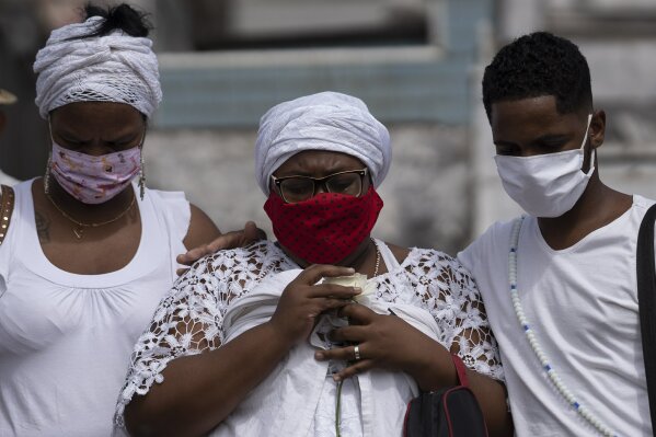 Taina dos Santos, center, attends the burial of her mother Ana Maria, a 56-year-old nursing assistant who died from the new coronavirus, in Rio de Janeiro, Brazil, Tuesday, April 28, 2020. Dos Santos said that the situation in the Salgado Filho public hospital where her mother worked is complicated and that some health workers have to buy their own protective gear. "She gave everything to her job until the very end," said the 27-year-old daughter. (AP Photo/Leo Correa)