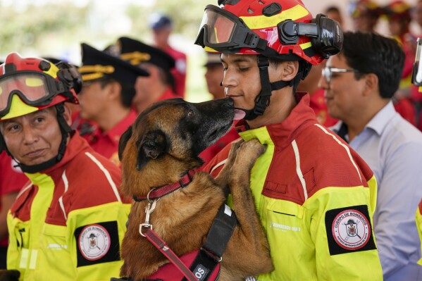 A dog named Ares licks its handler during a retirement ceremony for firefighter work dogs in Quito, Ecuador, Monday, May 20, 2024. The retired dogs were adopted by local residents. (AP Photo/Dolores Ochoa)