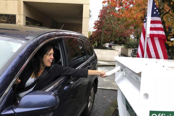 FILE - A voter in Lake Oswego, Ore., places her ballot in a designated drop box outside City Hall on Nov. 6, 2018. Lake Oswego is part of Oregon's new 6th U.S. House District. Democrats hope the new district will add to their advantage in Oregon. But Republicans also see an opportunity in November, hoping to capitalize on dissatisfaction with the party in power. (AP Photo/Gillian Flaccus, File)